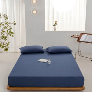 Drap-housse bleu marine installé sur un lit dans une chambre épurée