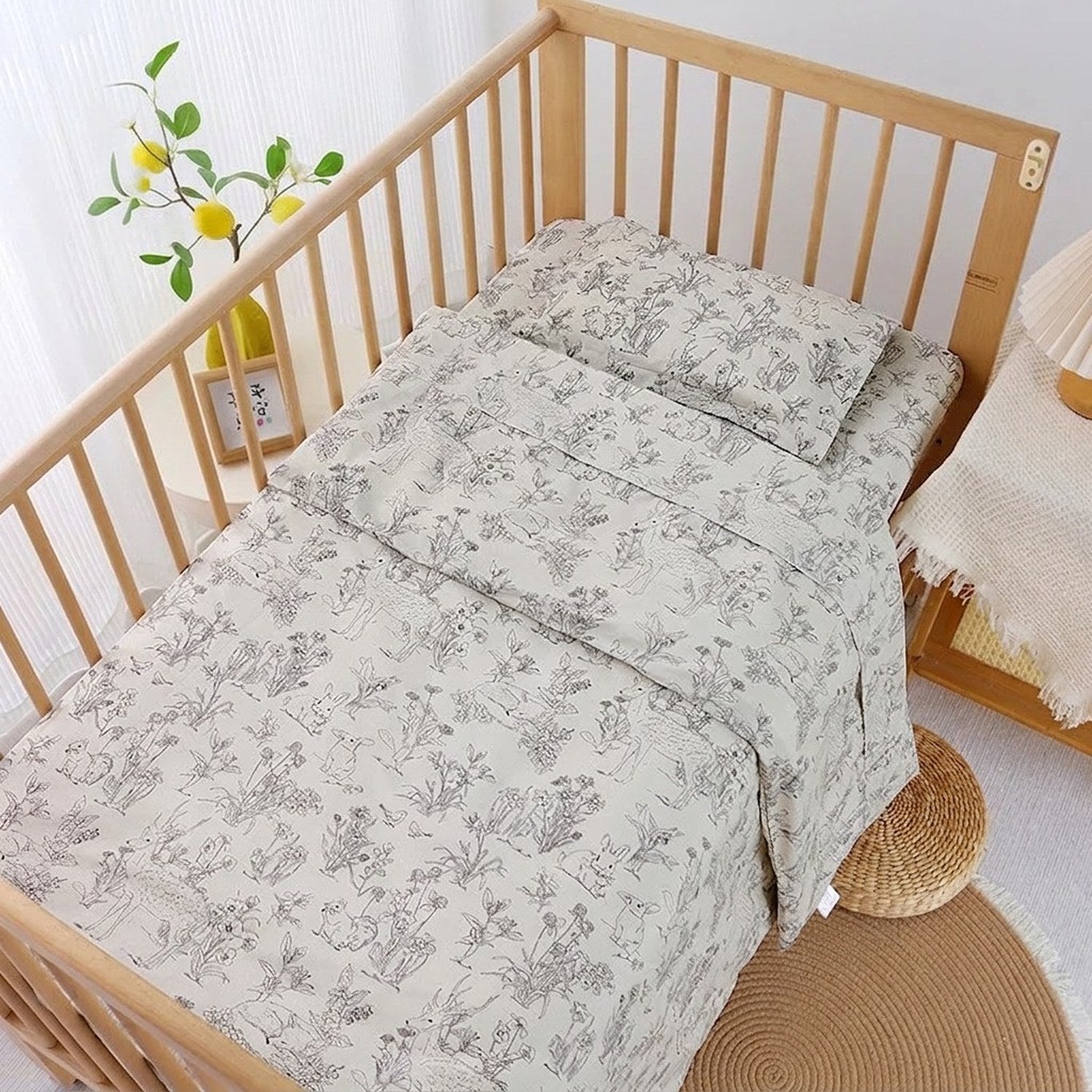 Parure de lit bébé motif nature au trait installée sur un lit à barreaux
