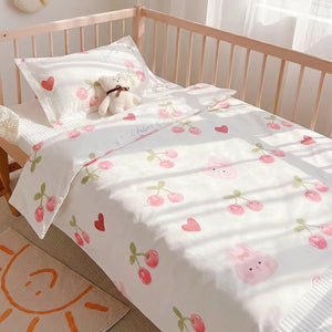 Parure de lit bébé motif lapin cerise en gros plan sur un lit à barreaux