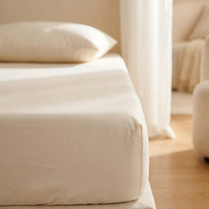 Drap-housse en coton doux posé sur un lit fait dans une chambre lumineuse et chaleureuse