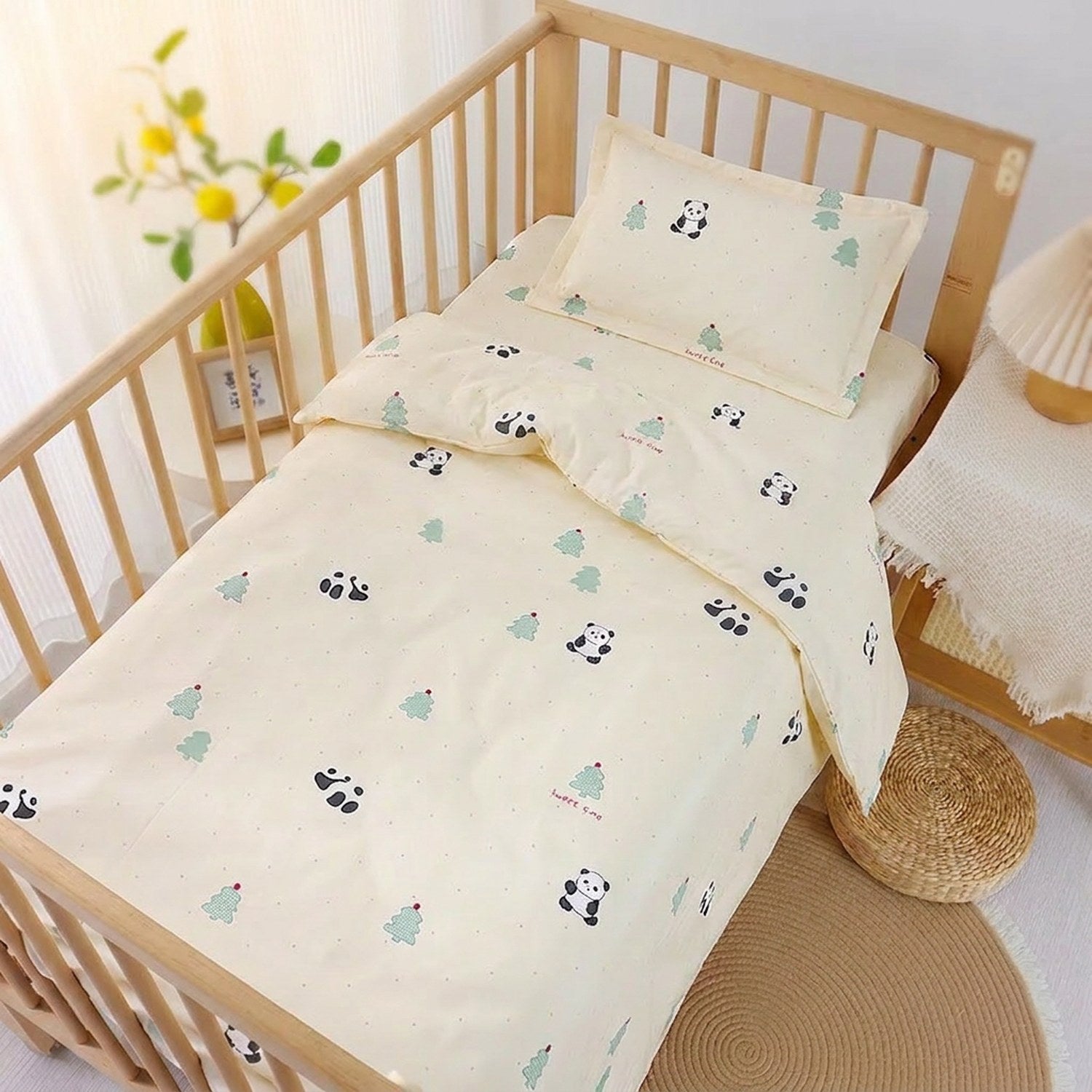 Parure de lit bébé au motif panda et sapins vert menthe installée sur un lit à barreaux