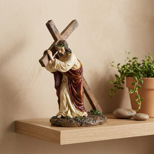 Statue de Jésus portant la croix sur une étagère murale en bois avec une plante verte