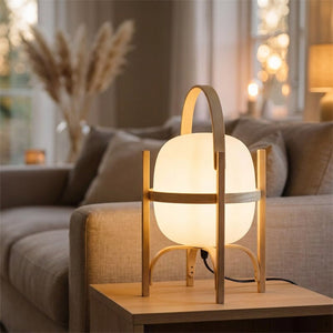 Lampe lanterne en bois allumee sur une table basse pres d un canape en lin
