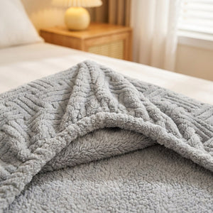 Coin replié d'un drap-housse gris en peluche gaufrée sur un lit dans une chambre chaleureuse
