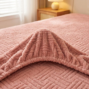 Coin replié d'un drap-housse rose poudré en peluche gaufrée montrant l'élastique