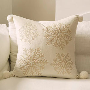 Housse de coussin brodée de flocons dorés sur canapé beige