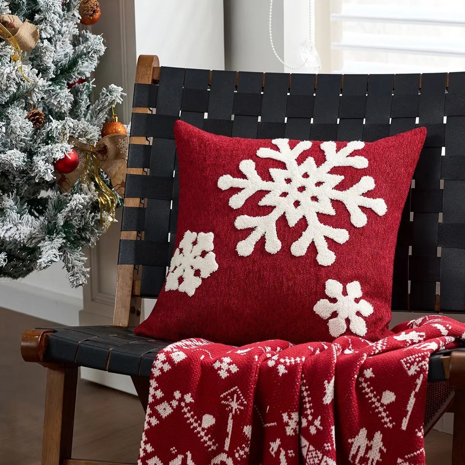 Housse de coussin rouge brodée de flocons blancs sur chaise en bois