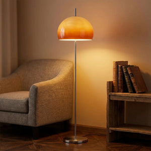 Lampadaire champignon orange allumé dans un coin lecture avec fauteuil et étagère