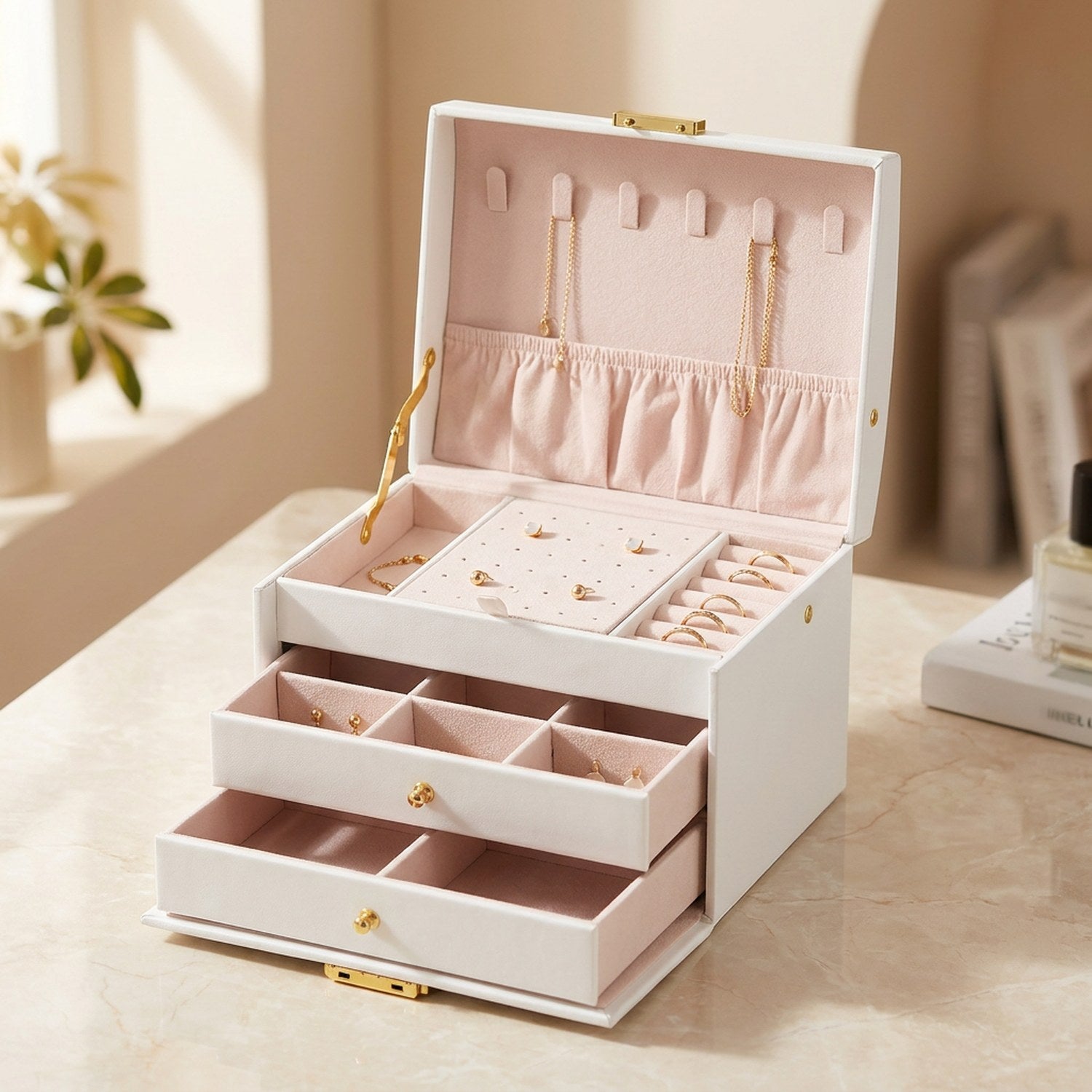Boîte à bijoux à trois niveaux en simili cuir blanc ouverte avec serrure dorée et intérieur rose