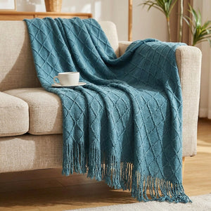 Couverture tricotée bleue à franges en maille losange sur un canapé