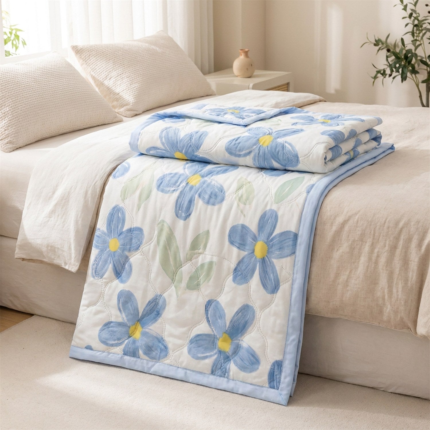 Couette d'été en coton lavé à fleurs bleues pliée sur un lit dans une chambre lumineuse
