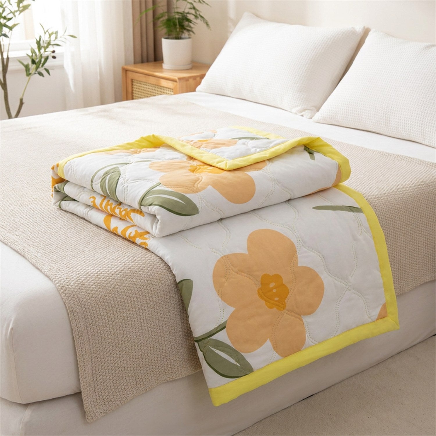 Couette d'été en coton lavé à fleurs oranges pliée sur un lit