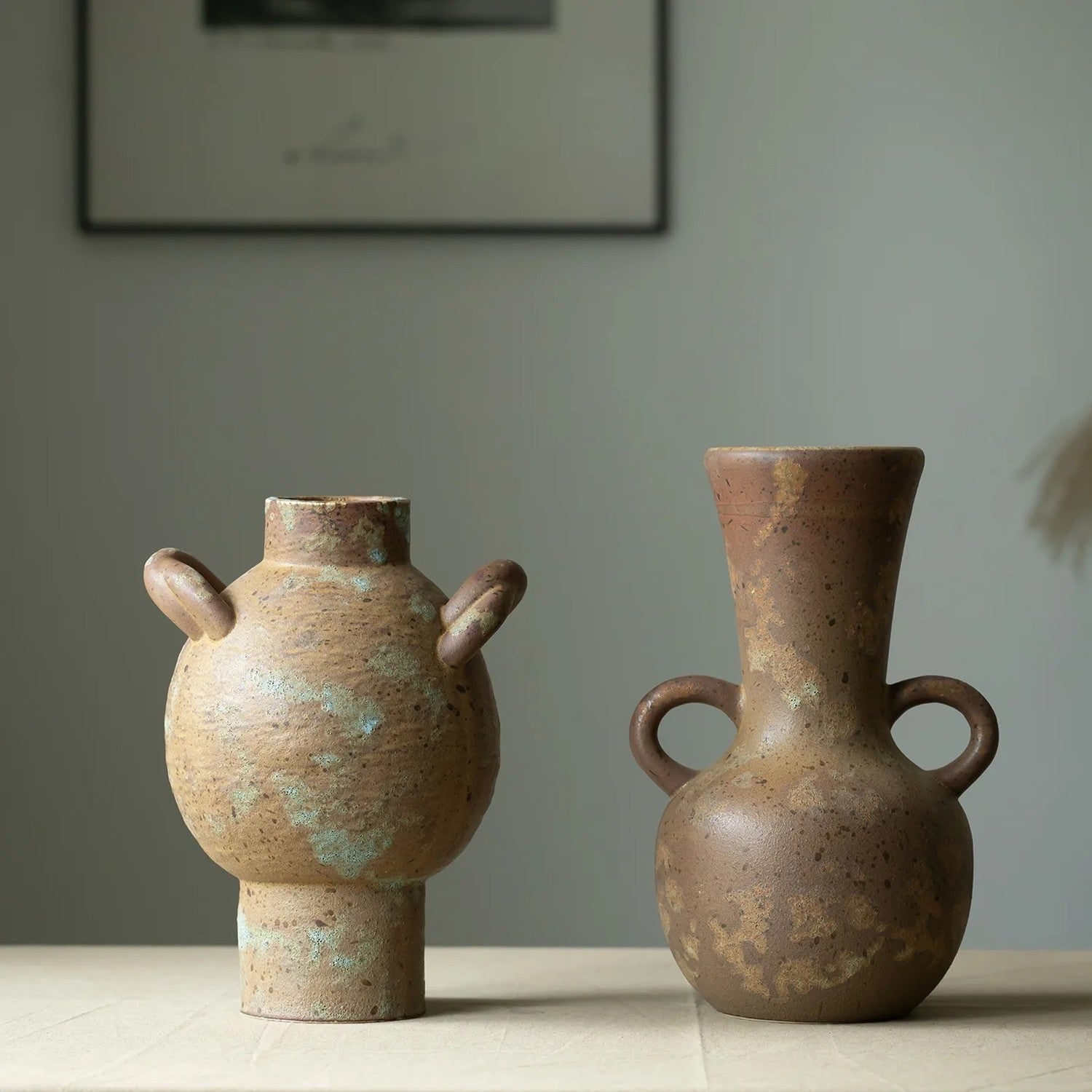 Deux vases grecs rustiques en céramique posés côte à côte sur une table en bois