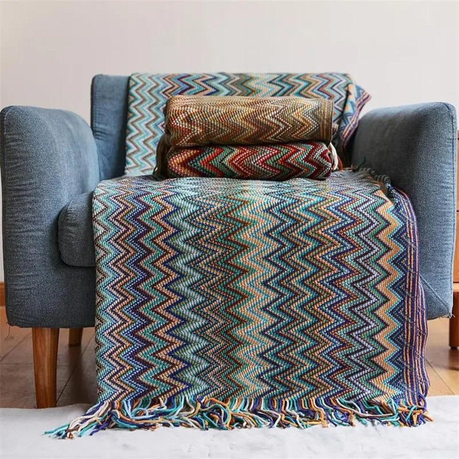 Plaid coloris bleu tricoté chevrons drapé sur un fauteuil bleu avec tasse