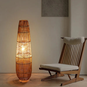 Lampadaire en rotin tressé éclairé près d'un fauteuil en bois dans une pièce épurée