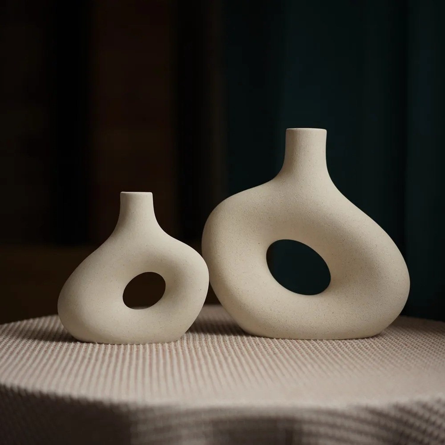 Petit et grand vase en céramique donut blanc cassé posés côte à côte