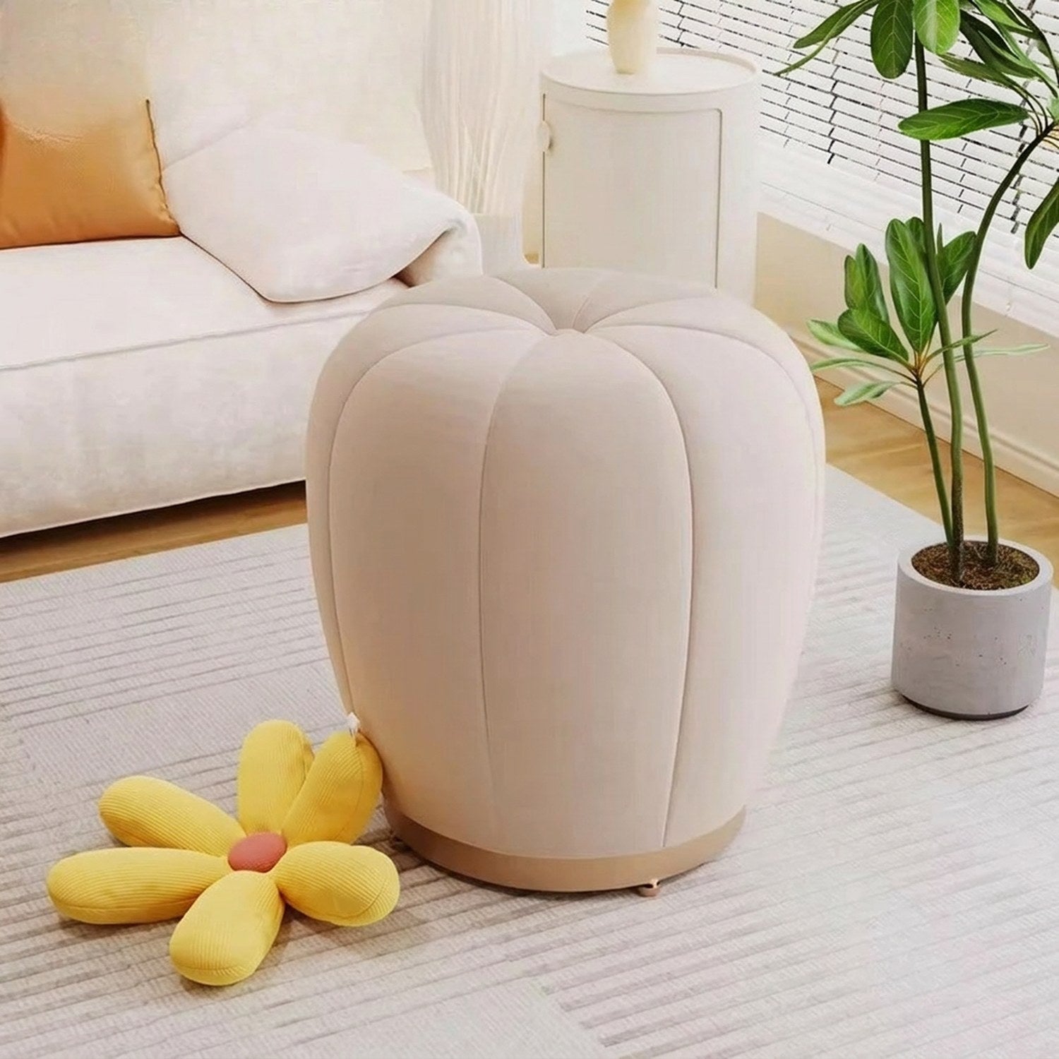 Pouf tabouret citrouille crème devant un canapé beige avec coussin moutarde