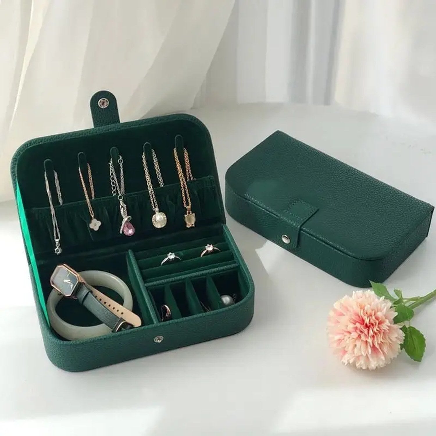 Boîte à bijoux voyage verte ouverte et fermée avec une fleur rose à côté