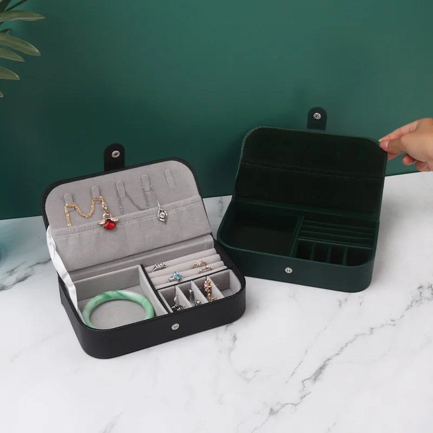 Boîtes à bijoux noire et verte ouvertes sur surface en marbre