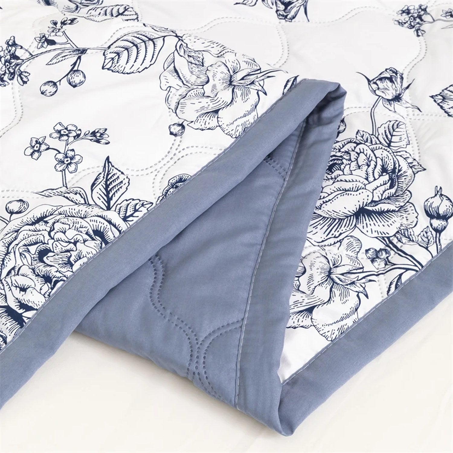Détail du motif floral bleuté et du revers bleu de la couette d'été matelassée