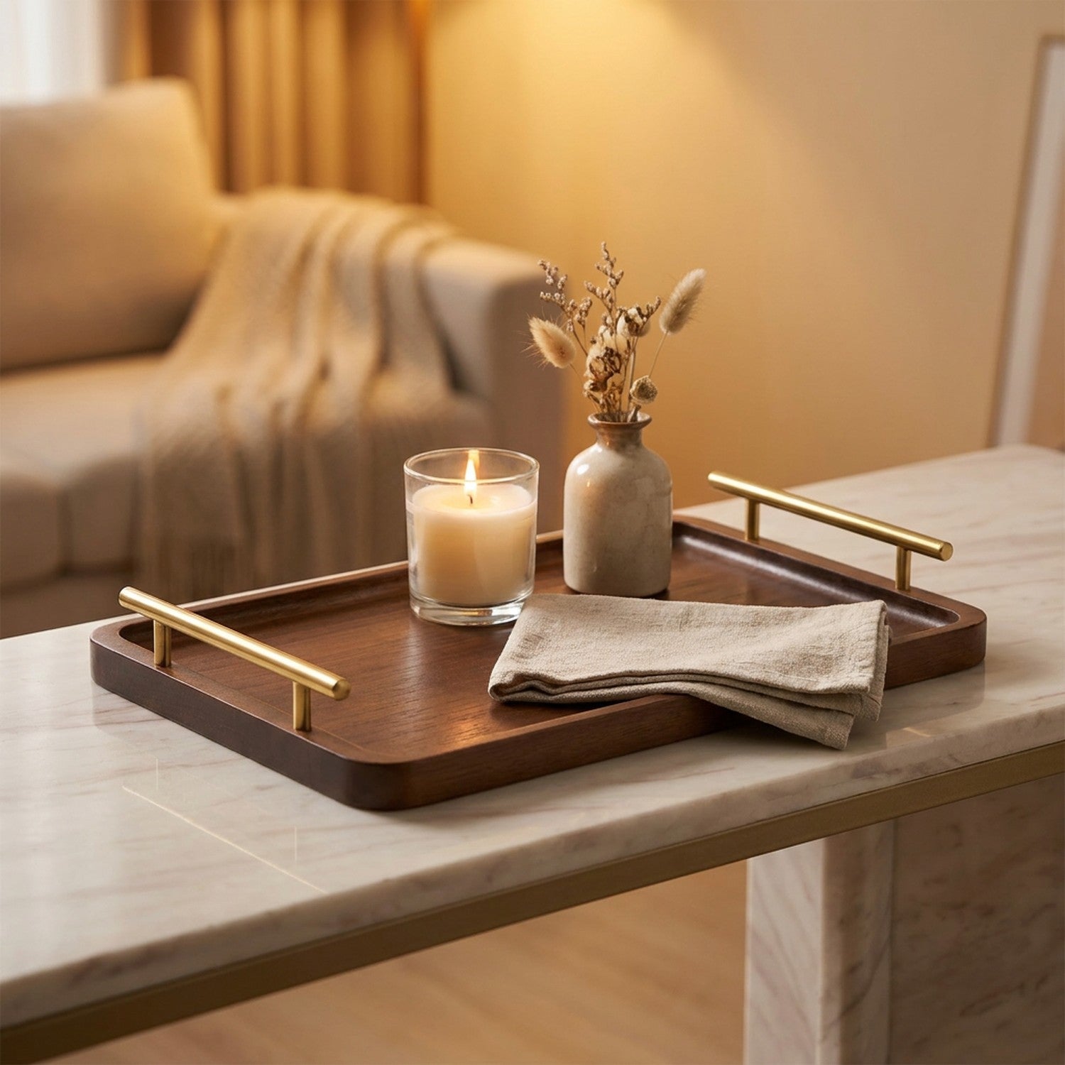 Plateau de service en bois foncé à poignées dorées avec une bougie et un vase sur une console en marbre