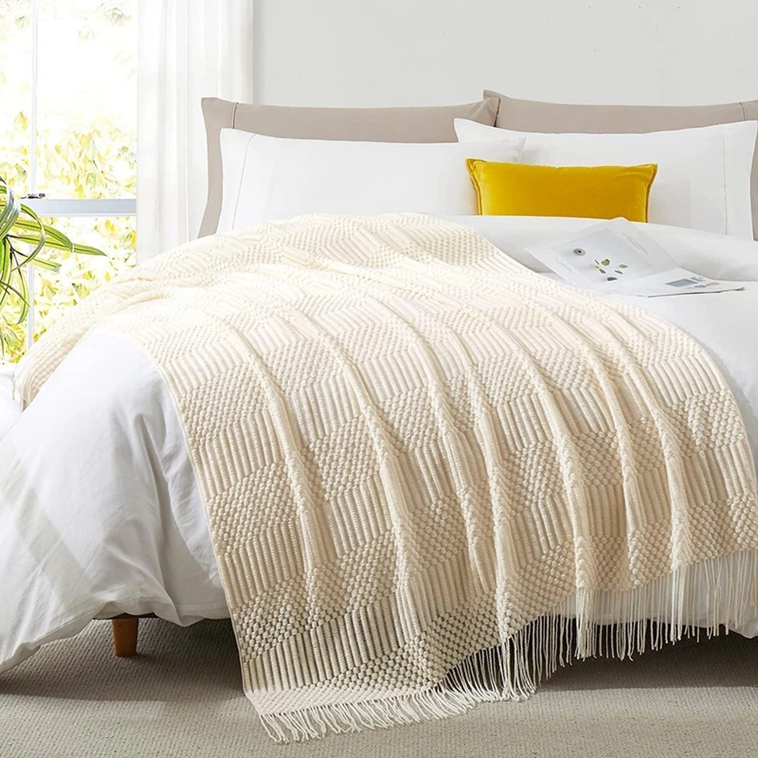 Plaid tricoté crème drapé sur un lit avec coussins