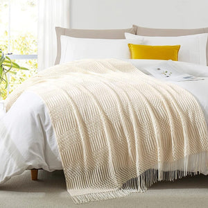 Plaid tricoté crème drapé sur un lit avec coussins