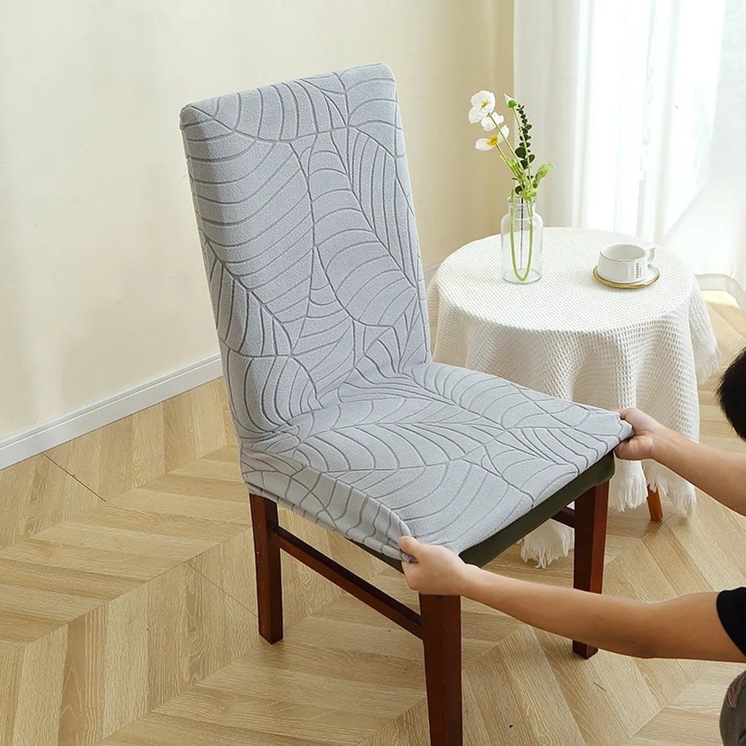 Installation de la housse de chaise sur une chaise en bois près d'une petite table