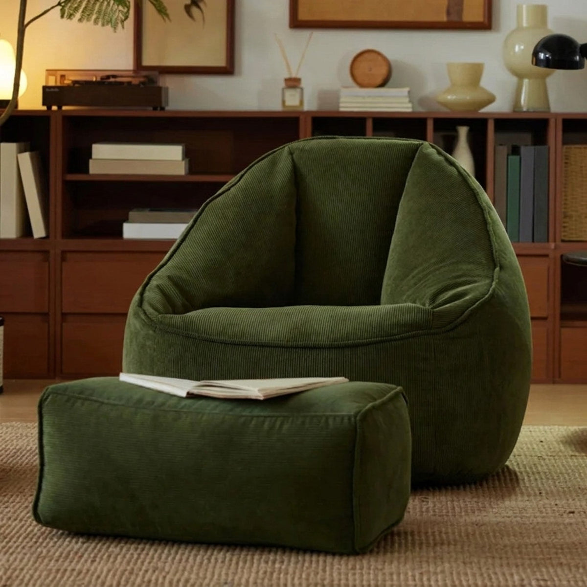 Fauteuil pouf et repose-pieds vert foncé en velours côtelé avec un livre ouvert