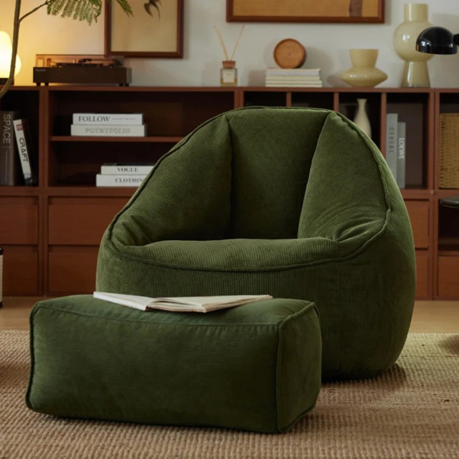 Fauteuil pouf et repose-pieds vert foncé en velours côtelé avec un livre ouvert