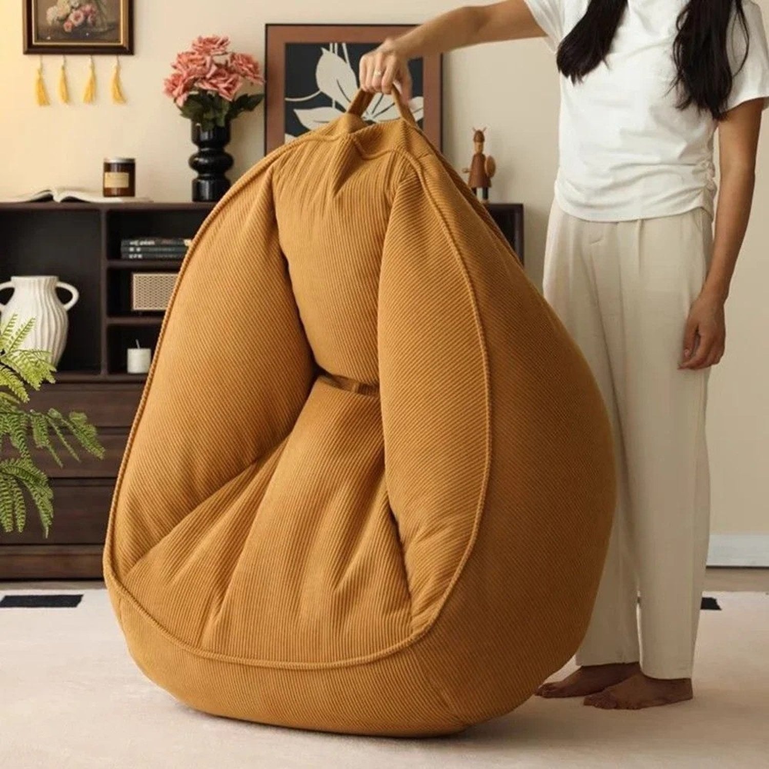 Fauteuil pouf doré porté par une personne grâce à sa poignée intégrée