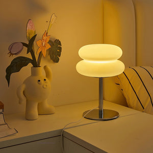 Lampe de chevet champignon allumée sur une table de nuit dans une chambre chaleureuse