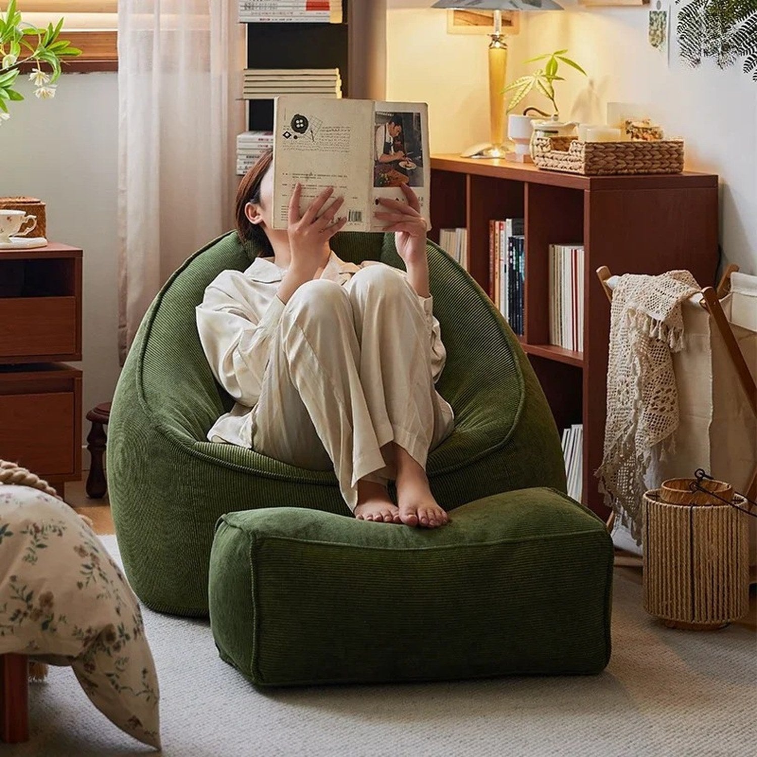 Personne assise dans le fauteuil pouf vert foncé en train de lire un livre