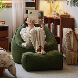 Personne assise dans le fauteuil pouf vert foncé en train de lire un livre