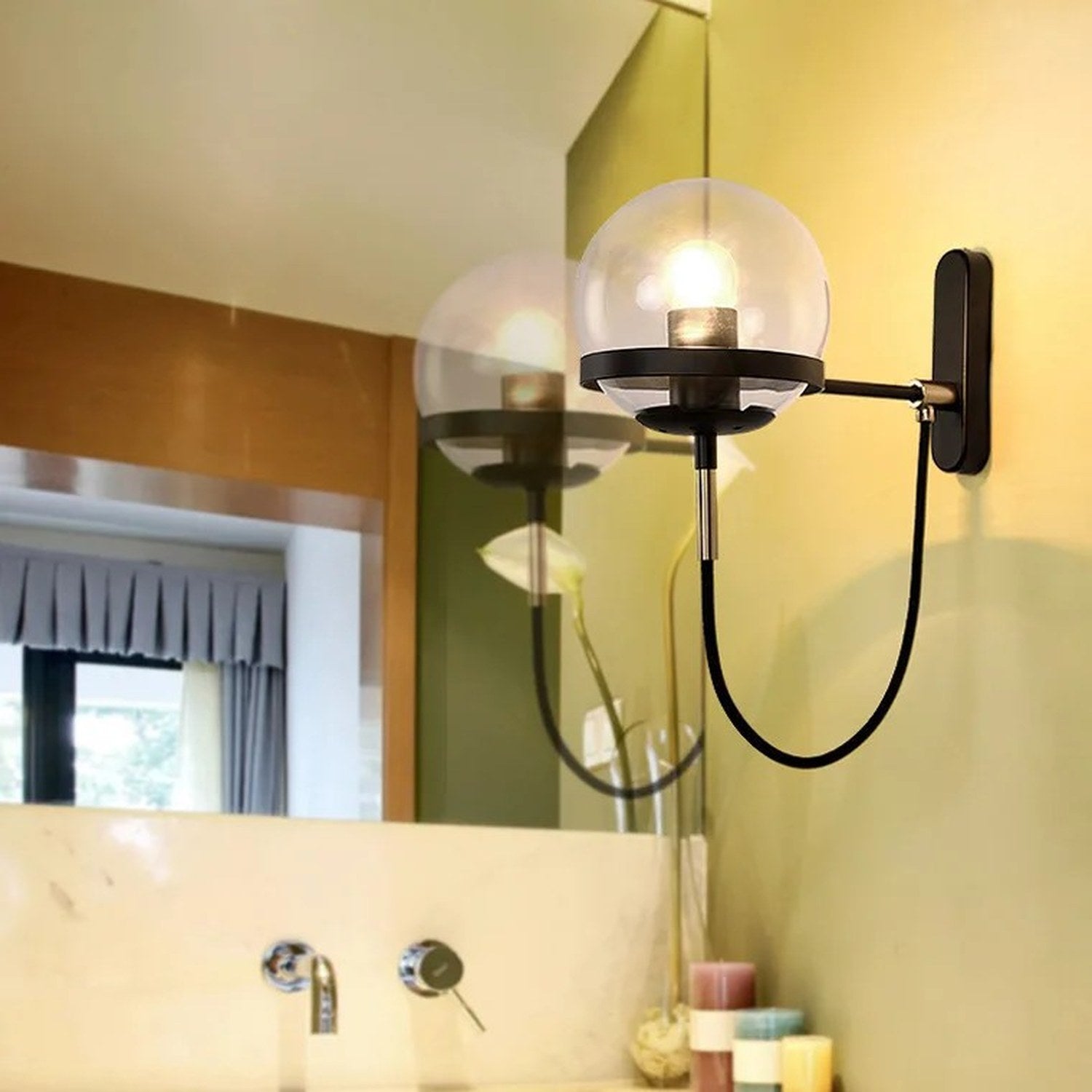 Applique murale boule de verre noire et dorée installée près d'un miroir de salle de bain