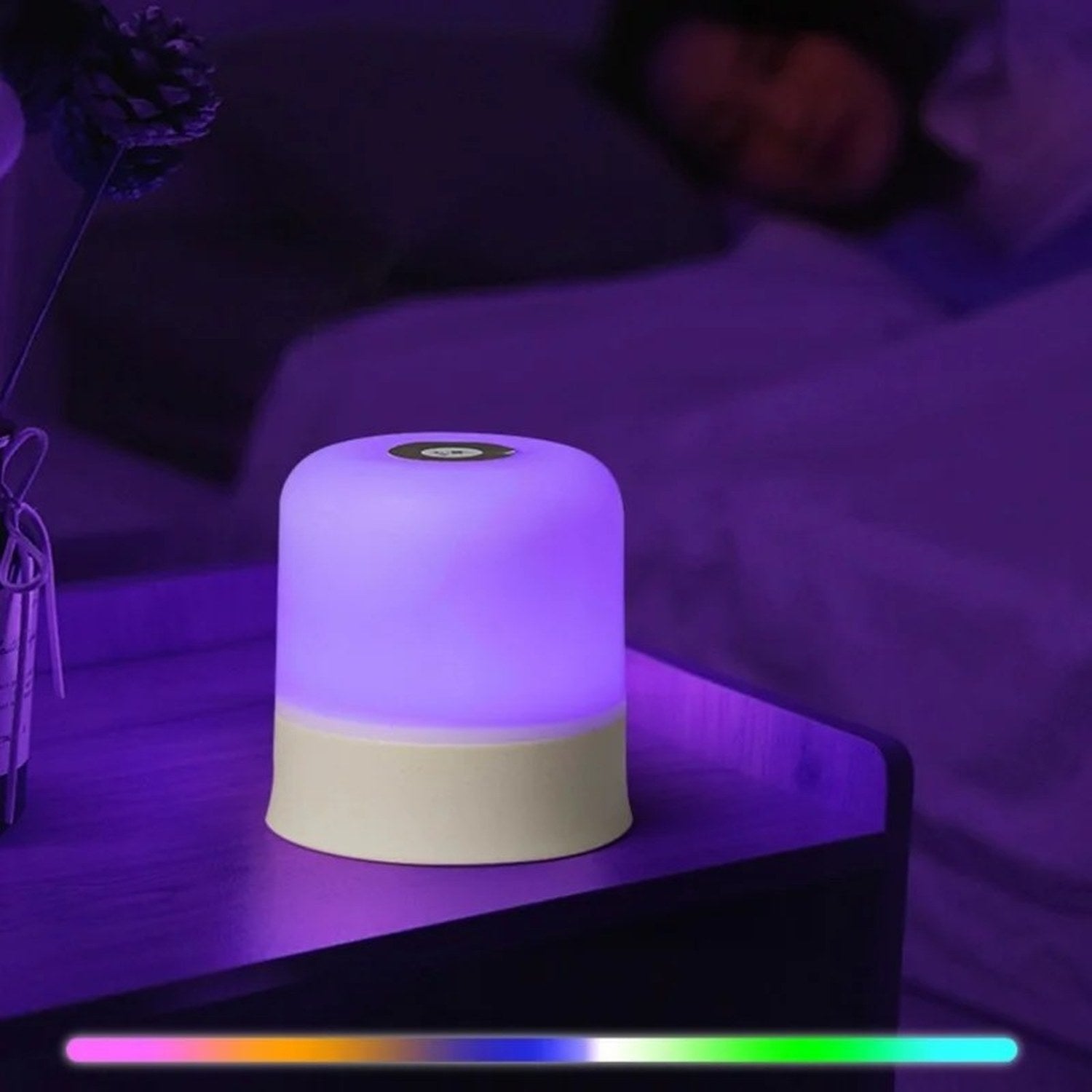 Lampe de chevet tactile allumée en violet sur une table de chevet la nuit