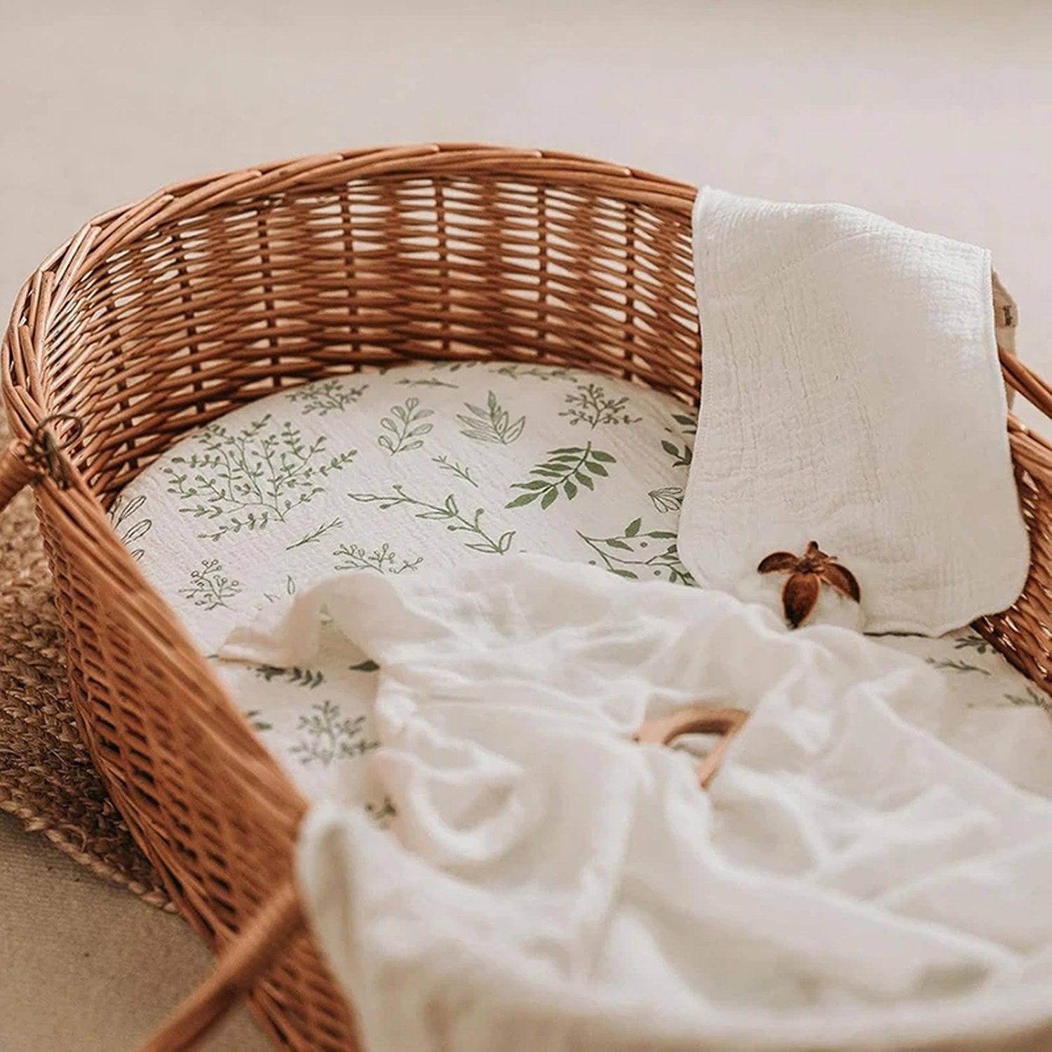 Panier Moïse en osier garni d un drap-housse en mousseline à feuillage vert et d un lange