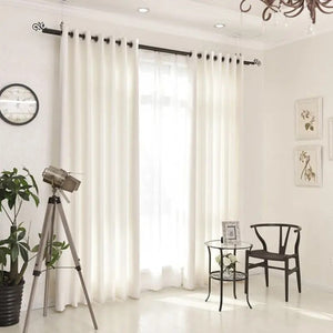 Rideau blanc dans un salon lumineux avec fauteuil et petite table