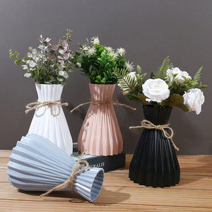 Quatre vases origami plissés de différentes couleurs avec des plantes vertes