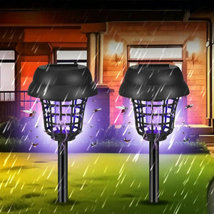 Deux lampes solaires anti-moustiques allumées devant une maison sous la pluie