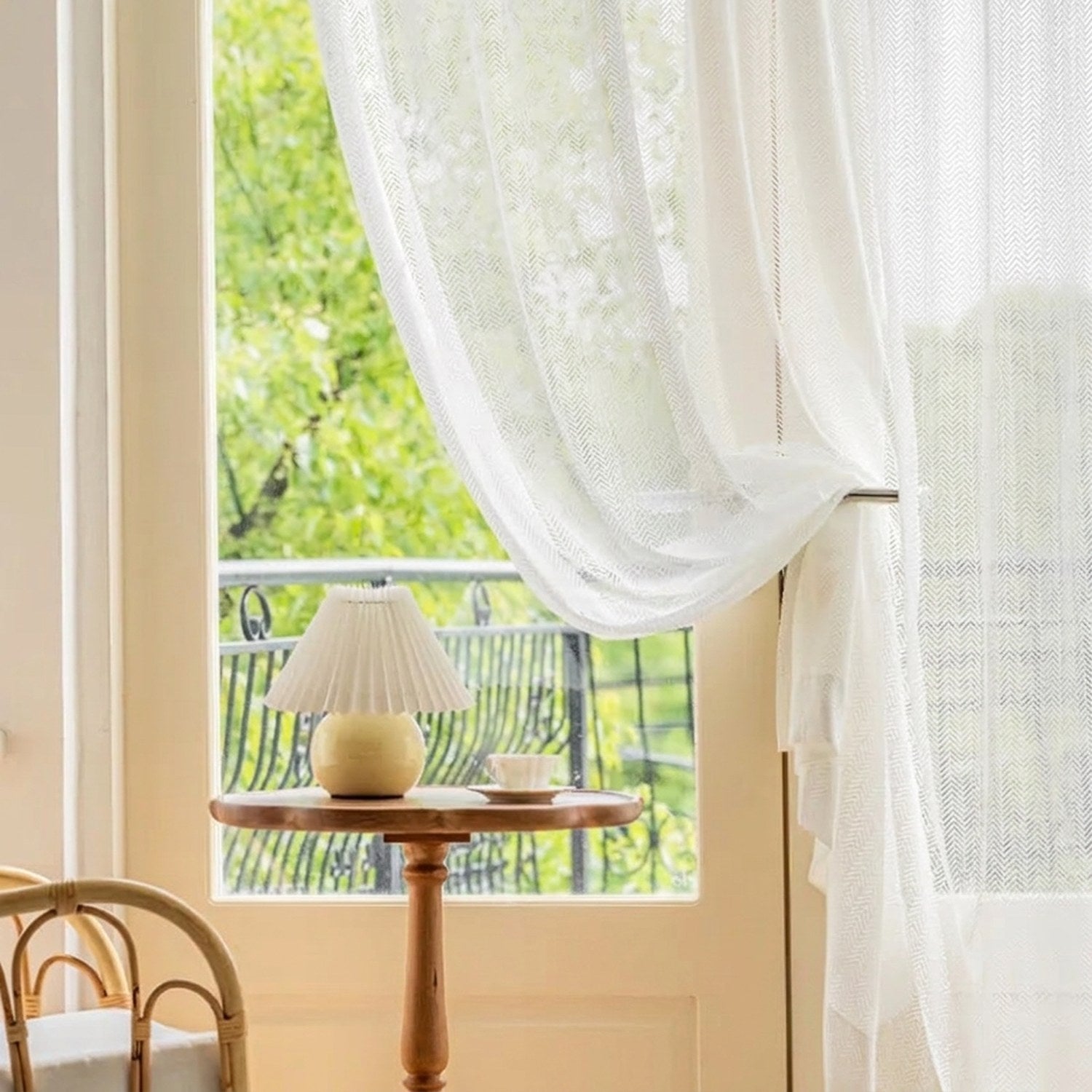 Rideau blanc noué près d'une fenêtre donnant sur un balcon verdoyant