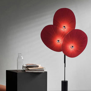 Lampadaire design 3 pétales rouge allumé sur fond neutre gris
