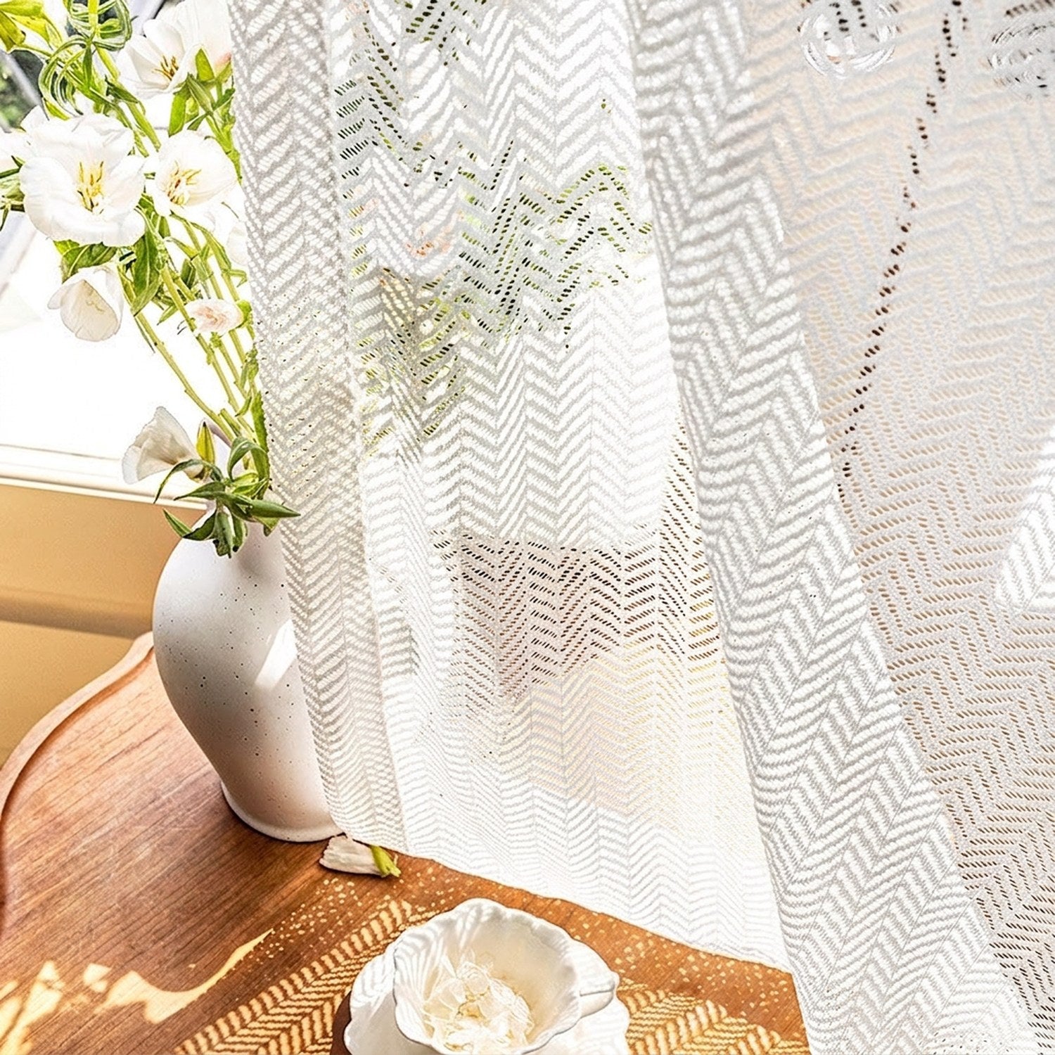 Détail du tissage chevrons du rideau blanc avec fleurs et vase en céramique
