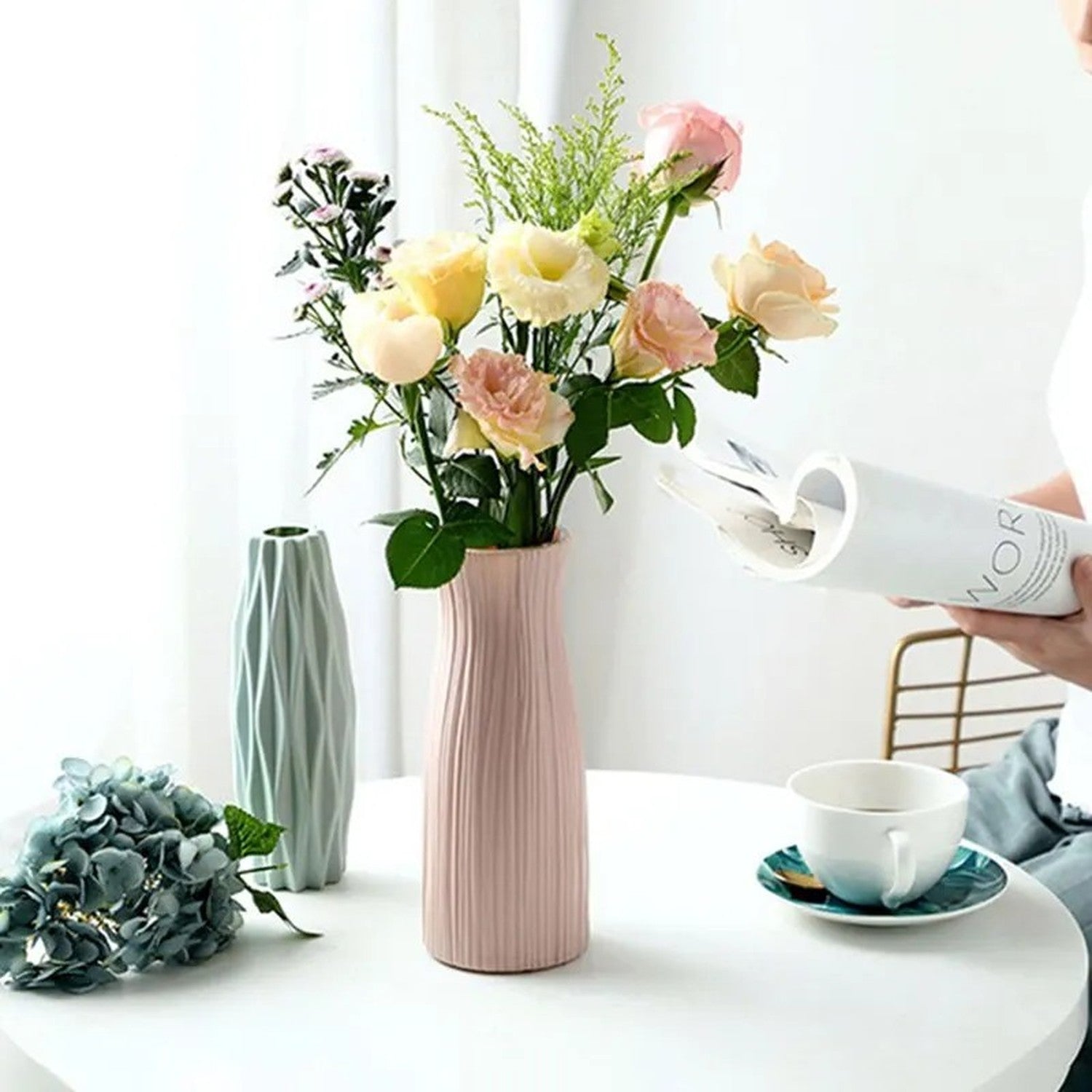 Vase à fleurs origami rose en situation sur une table avec un bouquet de roses