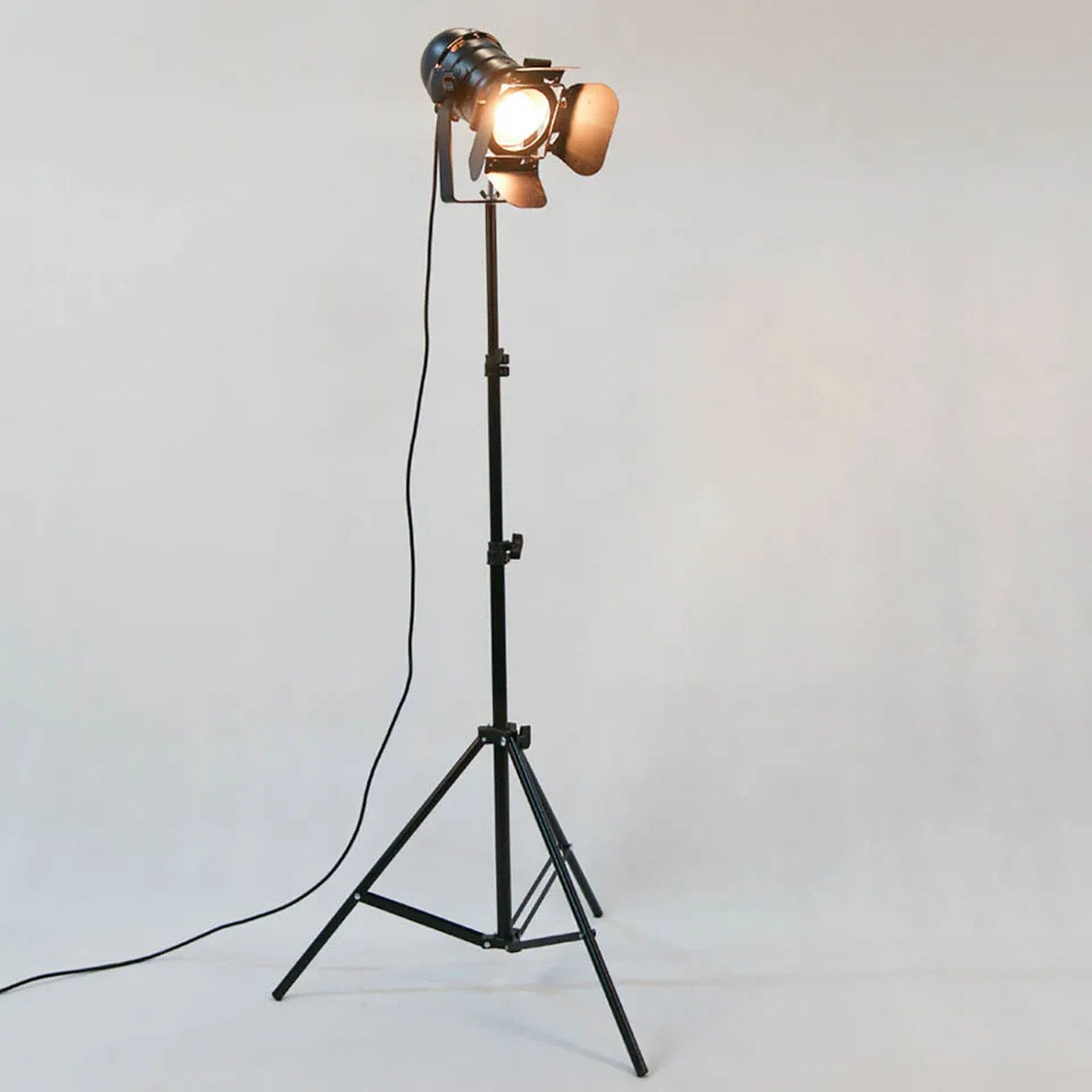 Lampadaire trépied projecteur noir fond gris référence