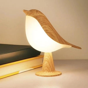 Lampe tactile oiseau posée près d'une pile de livres colorés