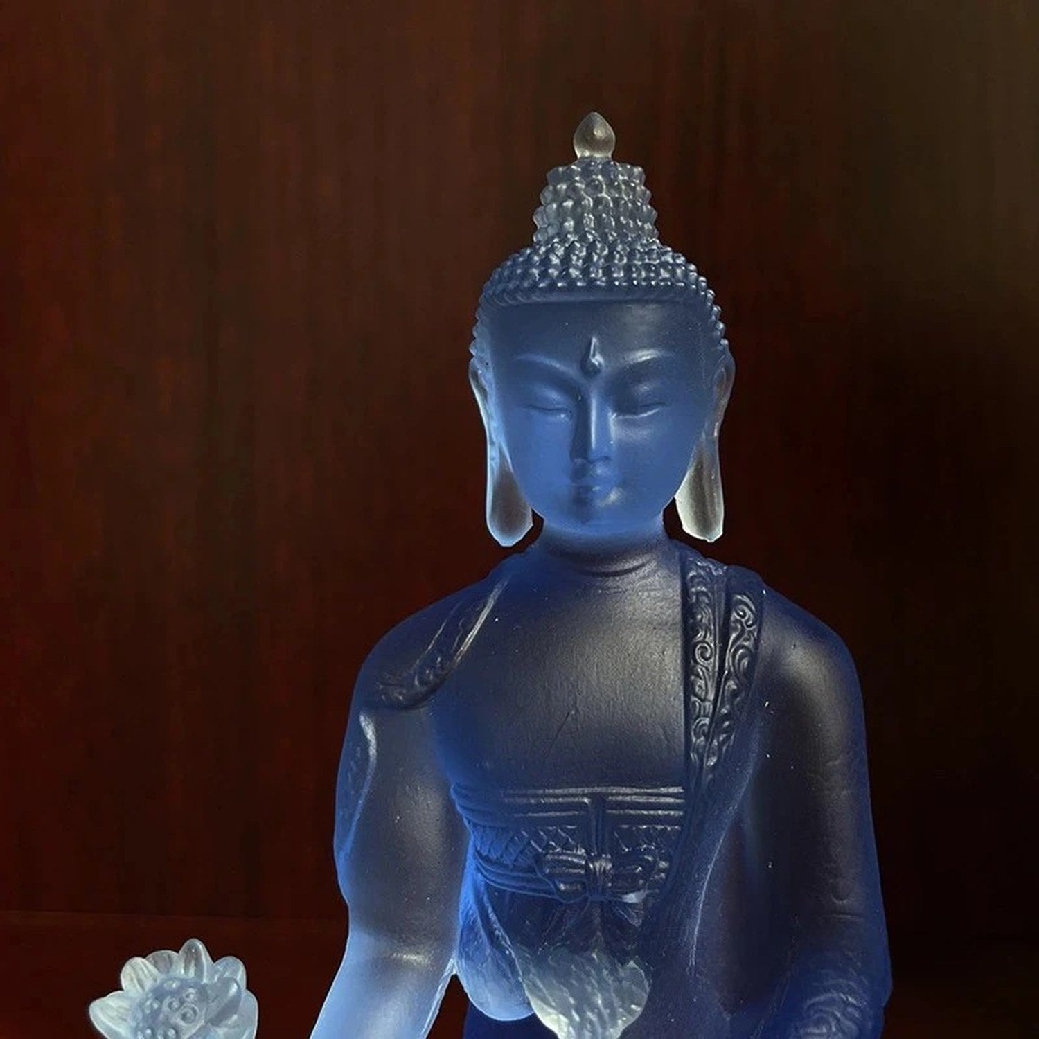 Détail du visage de la statuette bouddha bleu translucide, finition résine cristal
