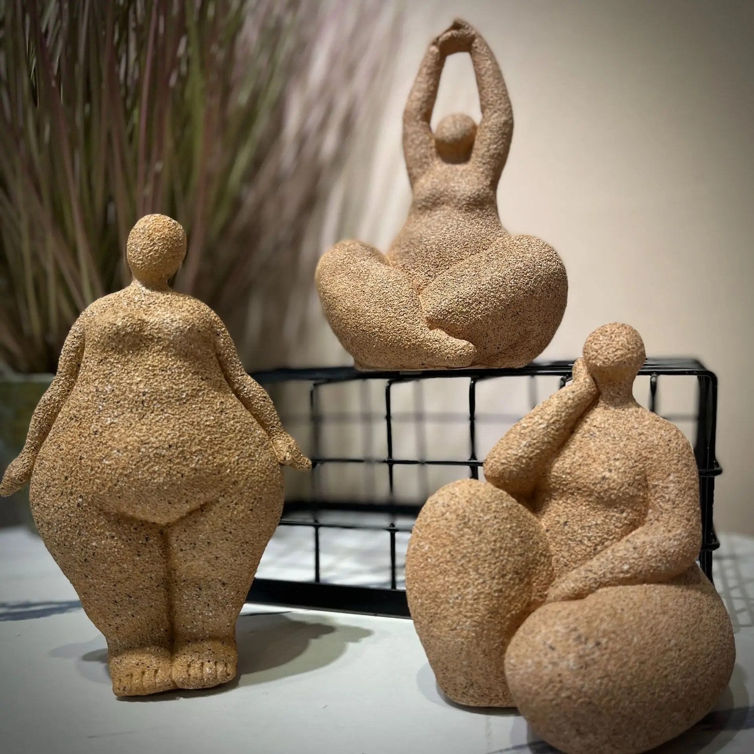 Trois statues de femme ronde terracotta dans des postures différentes sur un support