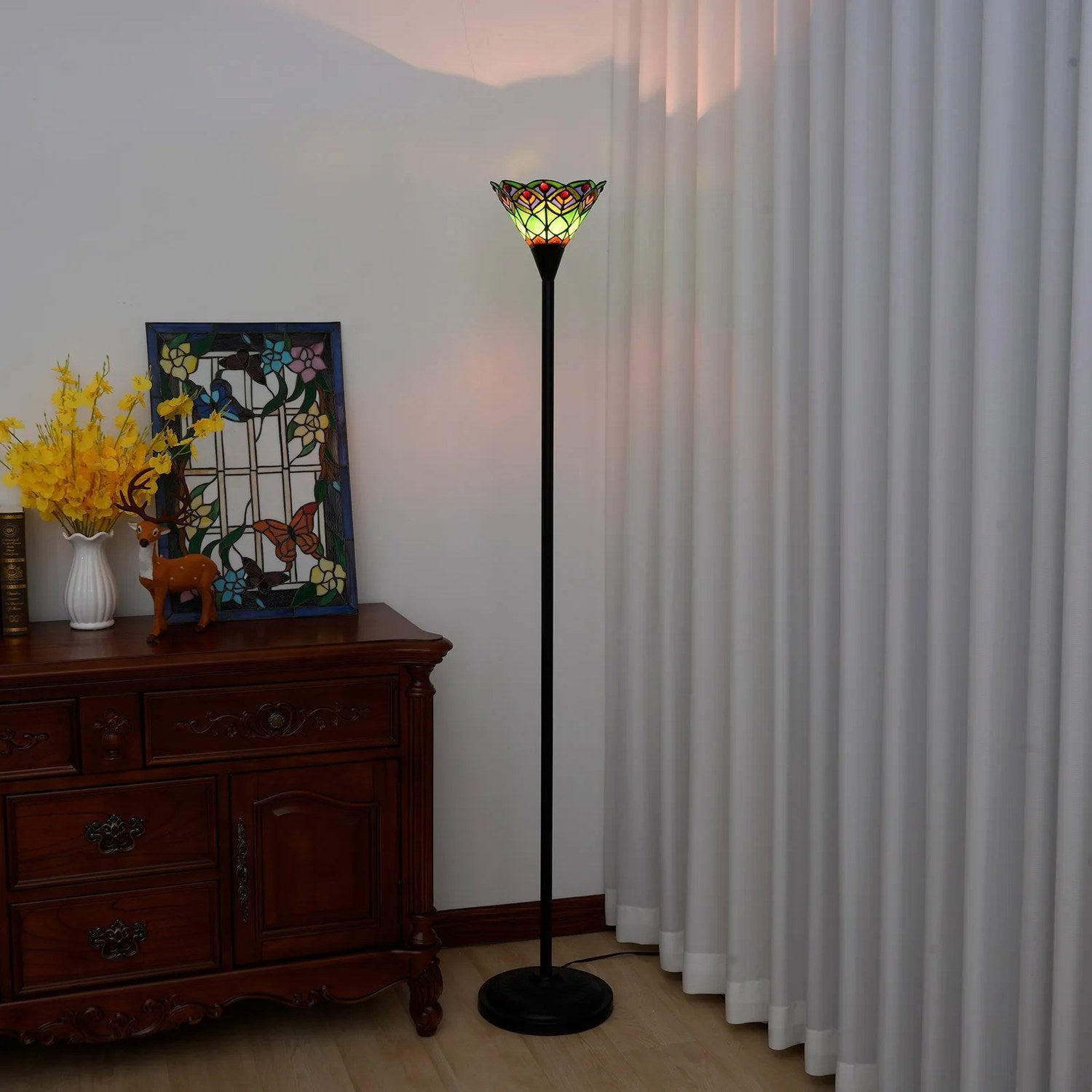 Lampadaire Tiffany vert allumé dans un intérieur vintage avec commode en bois et rideaux