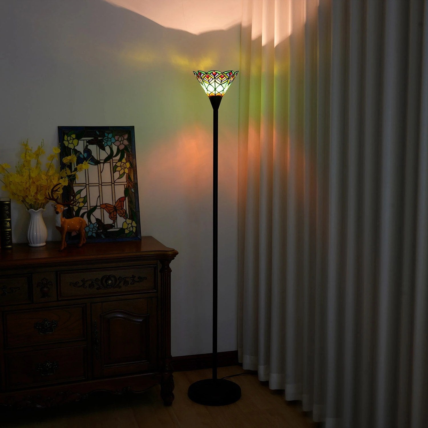 Lampadaire Tiffany vitrail allumé la nuit, reflets colorés projetés sur les rideaux